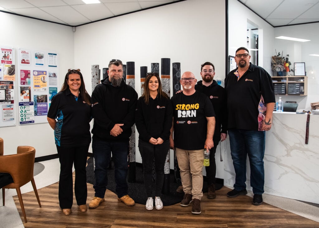 A group of six people standing together in a modern office or community centre